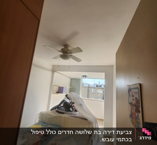 חדר עם רהיטים מכוסים בניילון לקראת צביעה